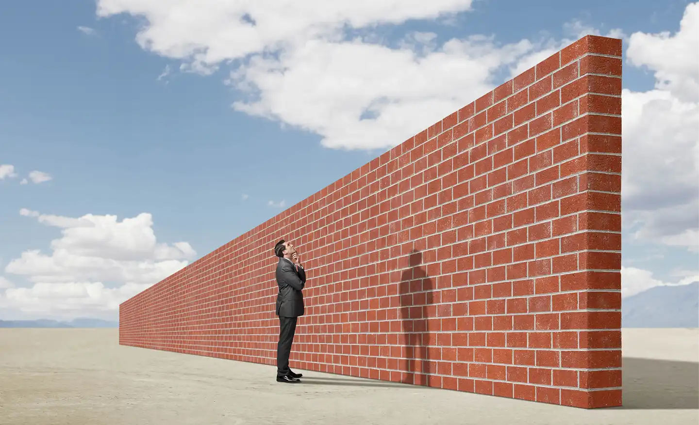 Image d'un humain devant un grand et long mur de briques, se demandant comment le franchir